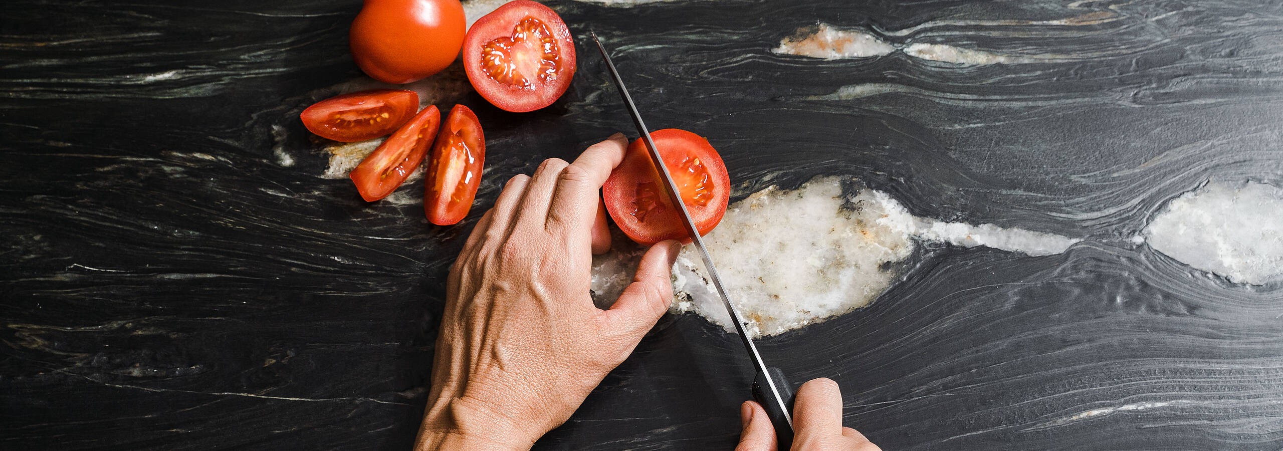 [Translate to English:] Tomaten werden auf einem Küchentisch geschnitten